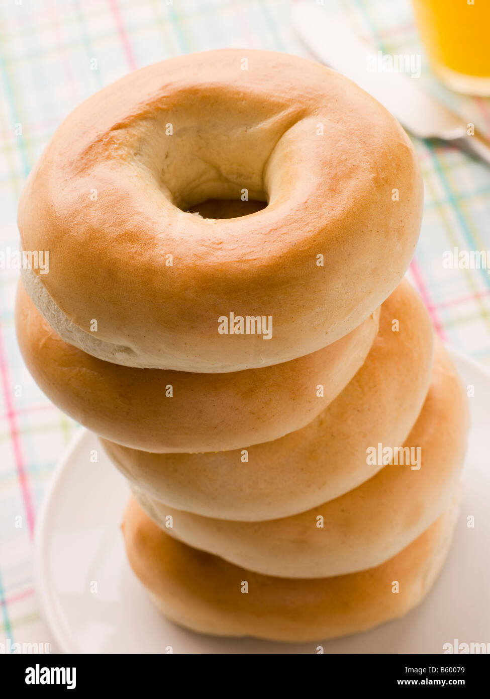 Stack of Plain Bagels with a Glass of Orange Juice Stock Photo