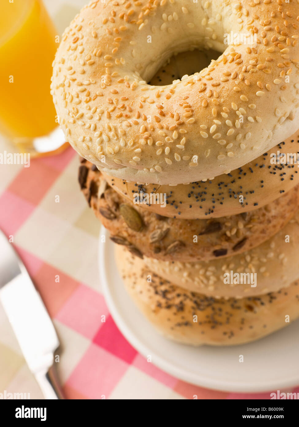 Stack of Seeded Bagels with a Glass of Orange Juice Stock Photo