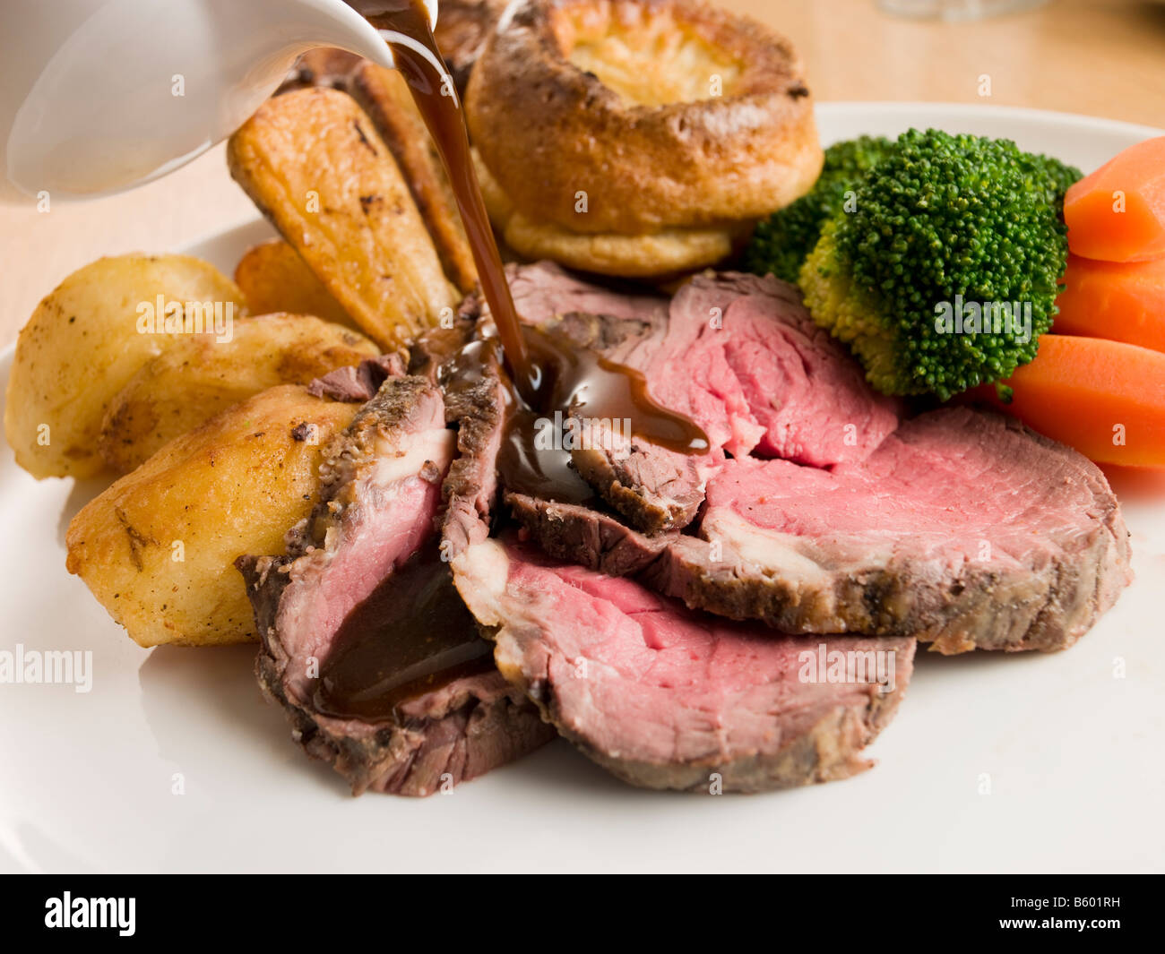 Gravy being Poured on a plate of Roast Beef and Yorkshire Pudding Stock