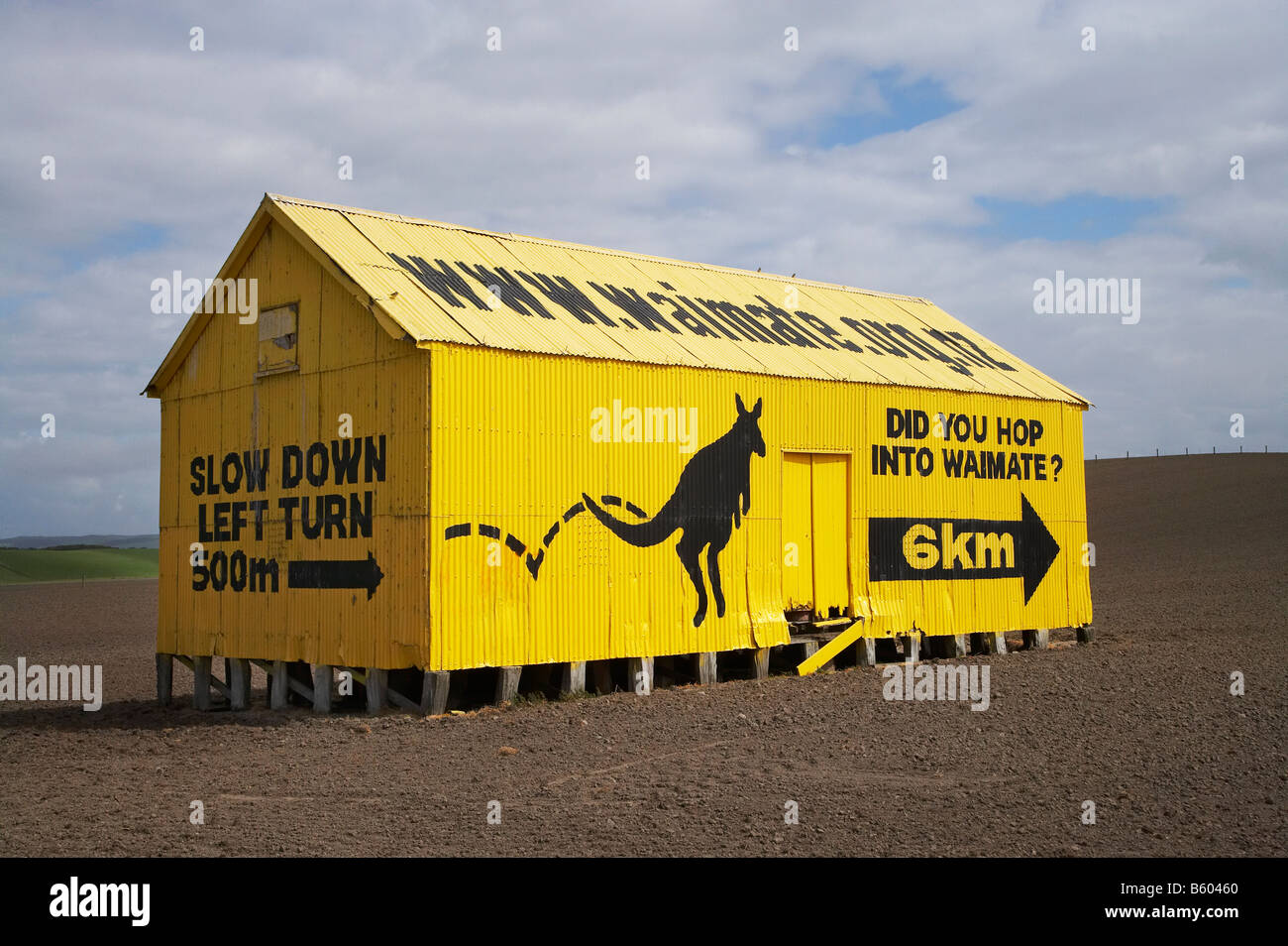 Sign to Waimate on Yellow Corrugated Iron Farm Shed State Highway One South Canterbury South Island New Zealand Stock Photo