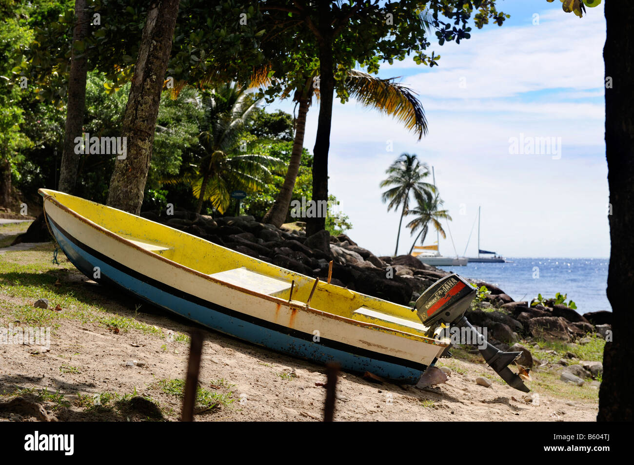 A SMALL FISHING BOAT IN THE COLOURS OF THE ST LUCIAN FLAG BY FORBIDDEN BEACH AT THE JALOUSIE PLANTATION RESORT ST LUCIA Stock Photo