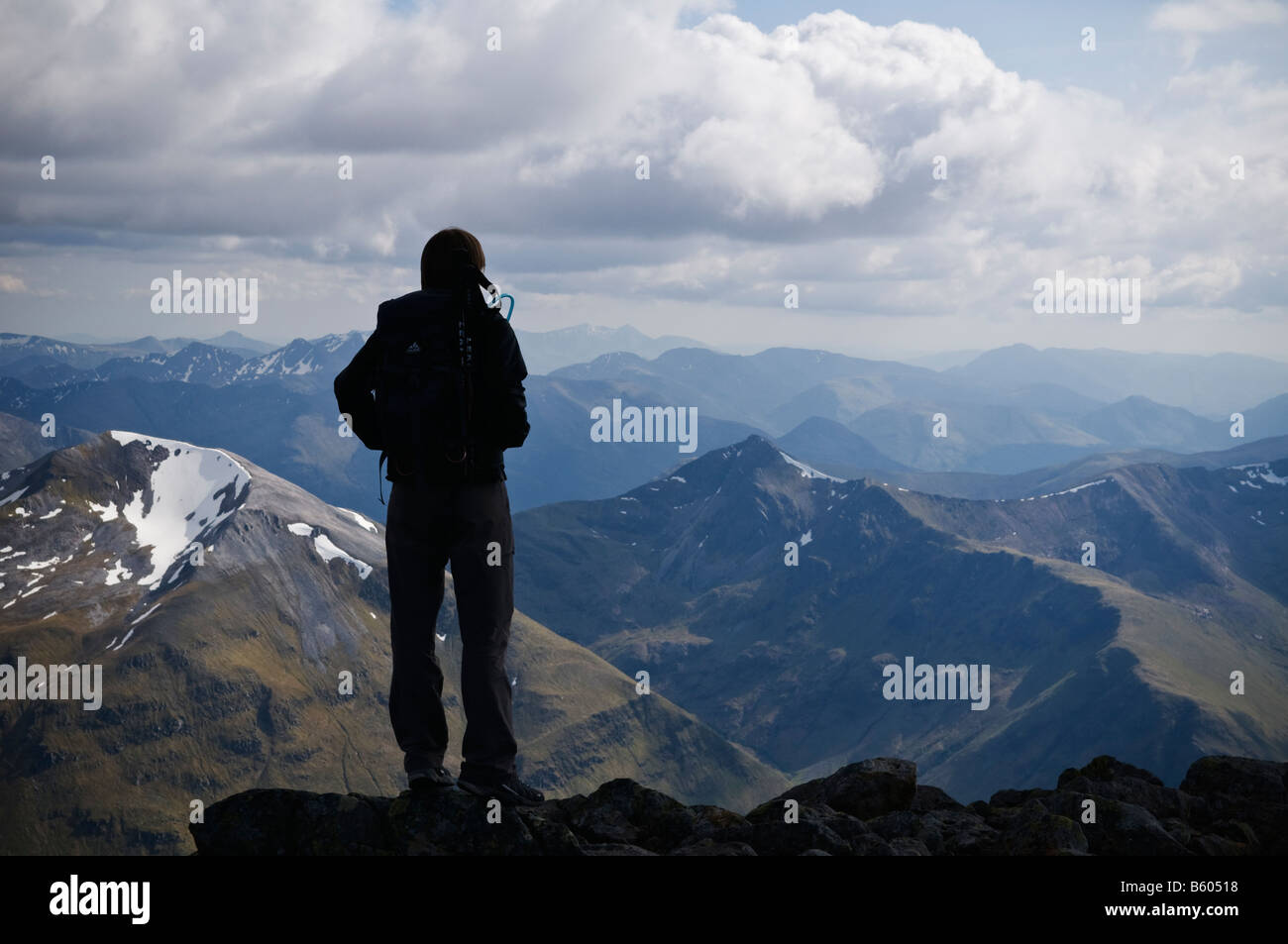 Silhouette of female hiker on summit of Ben Nevis looks across to the Mamores, Lochaber, Scotland Stock Photo
