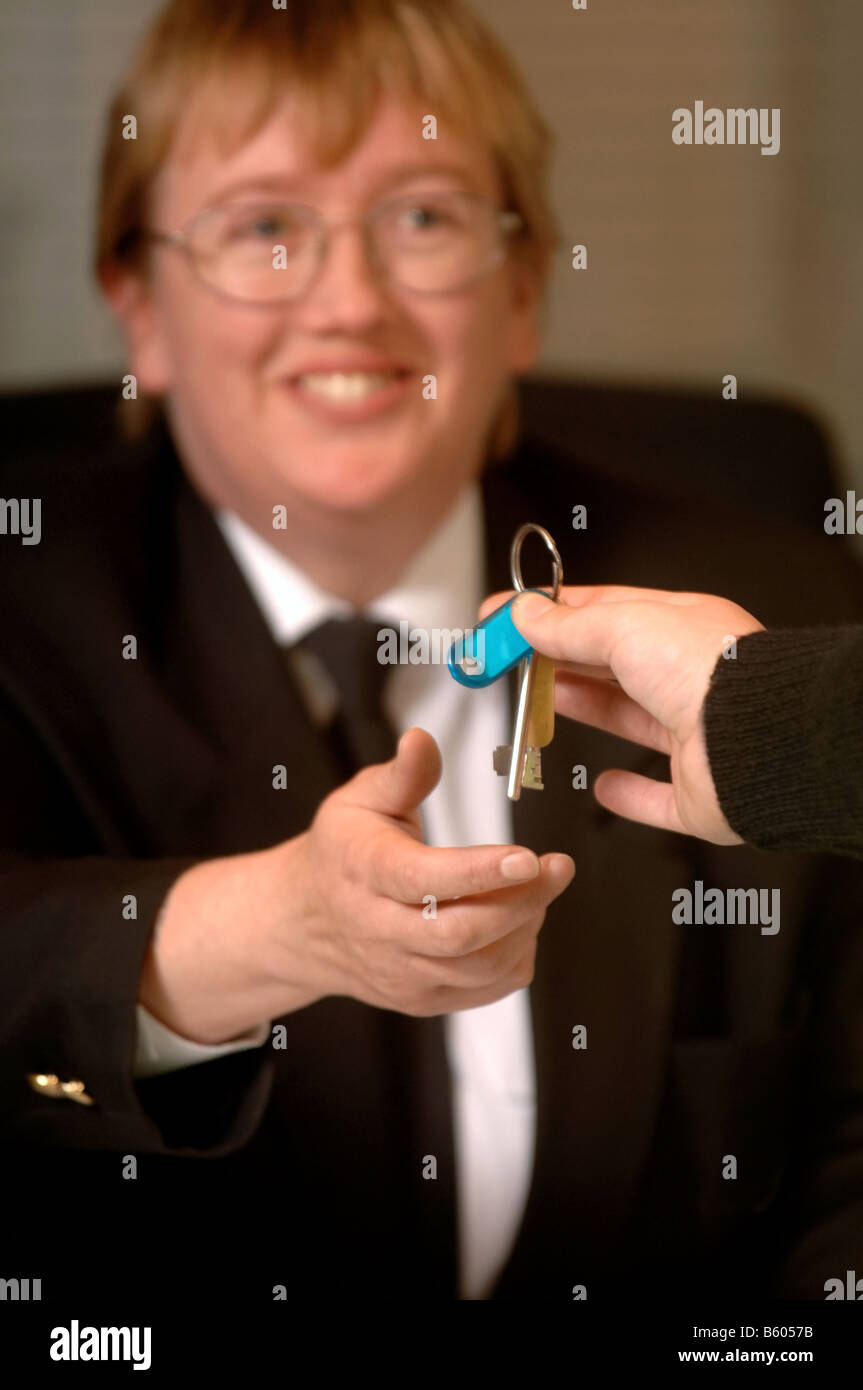 A SECURITY GUARD ON PATROL PASSES KEYS TO A FRONT DESK SECURITY OFFICER AT A BUSINESS PREMISES UK Stock Photo