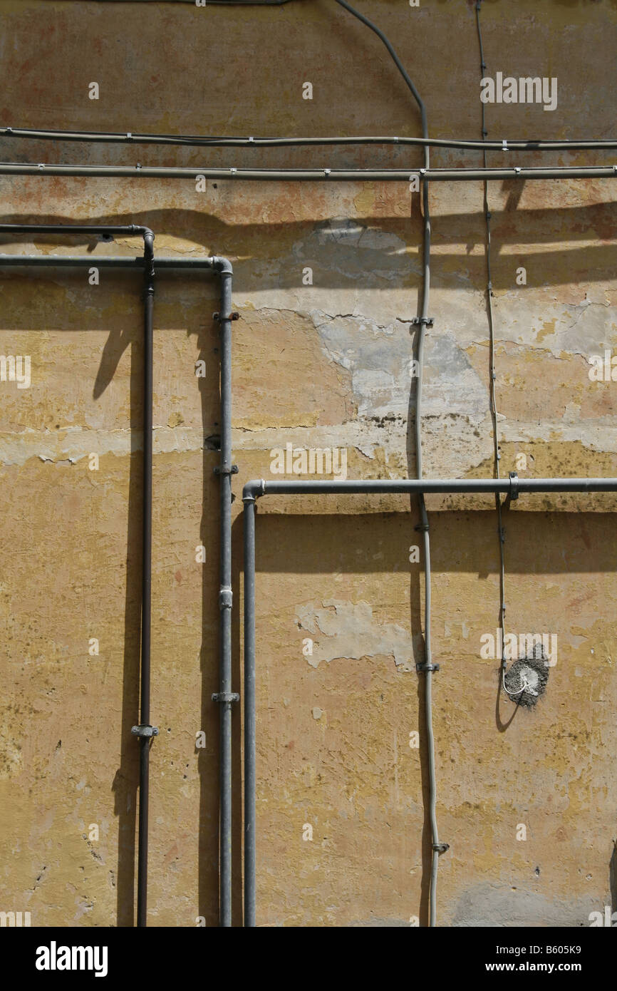electricity power wiring circuit pipes tubes on side of property wall in sun Stock Photo Alamy