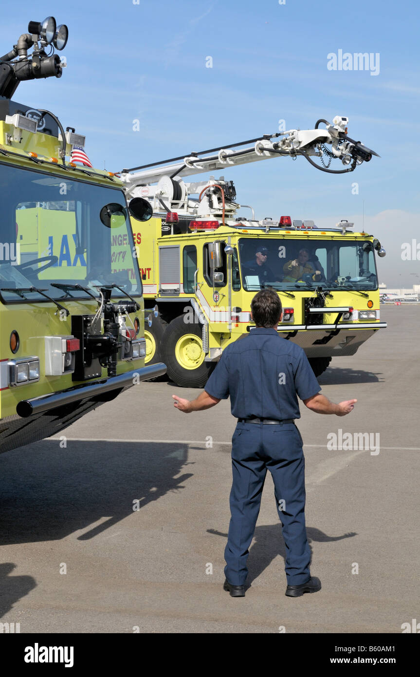 Fire fighter communicating with drivers of two new fire fighting trucks at Los Angeles International Airport Stock Photo