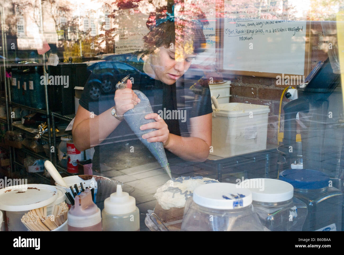 A Bakery Chef prepares a birthday cake as seen through the front window of Claire's Cornercopia in New Haven CT USA Stock Photo
