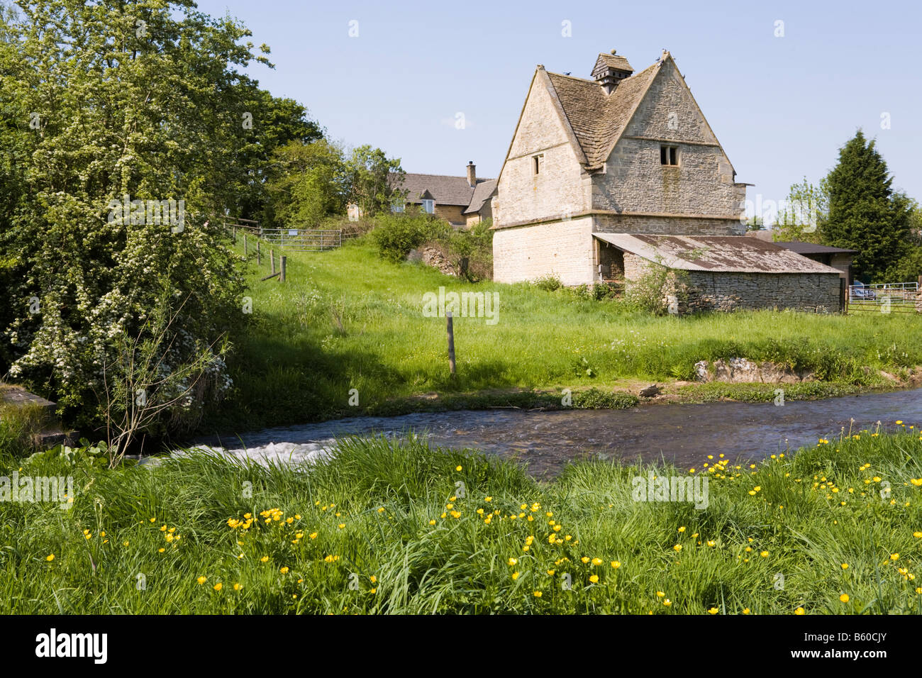 The old dovecote (c.1600 AD) by the River Windrush as it flows past the Cotswold village of Naunton, Gloucestershire Stock Photo