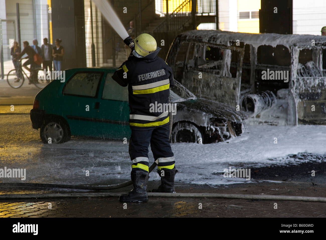 Fireman extinguishing, fire-brigade deployment on two burning cars underneath a bridge, Berlin Stock Photo
