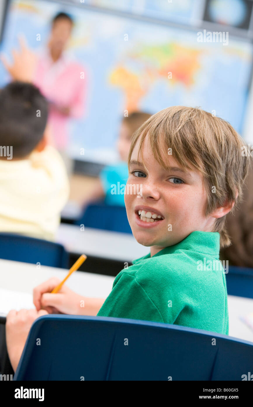 Student in class looking at camera with teacher in background (selective focus) Stock Photo