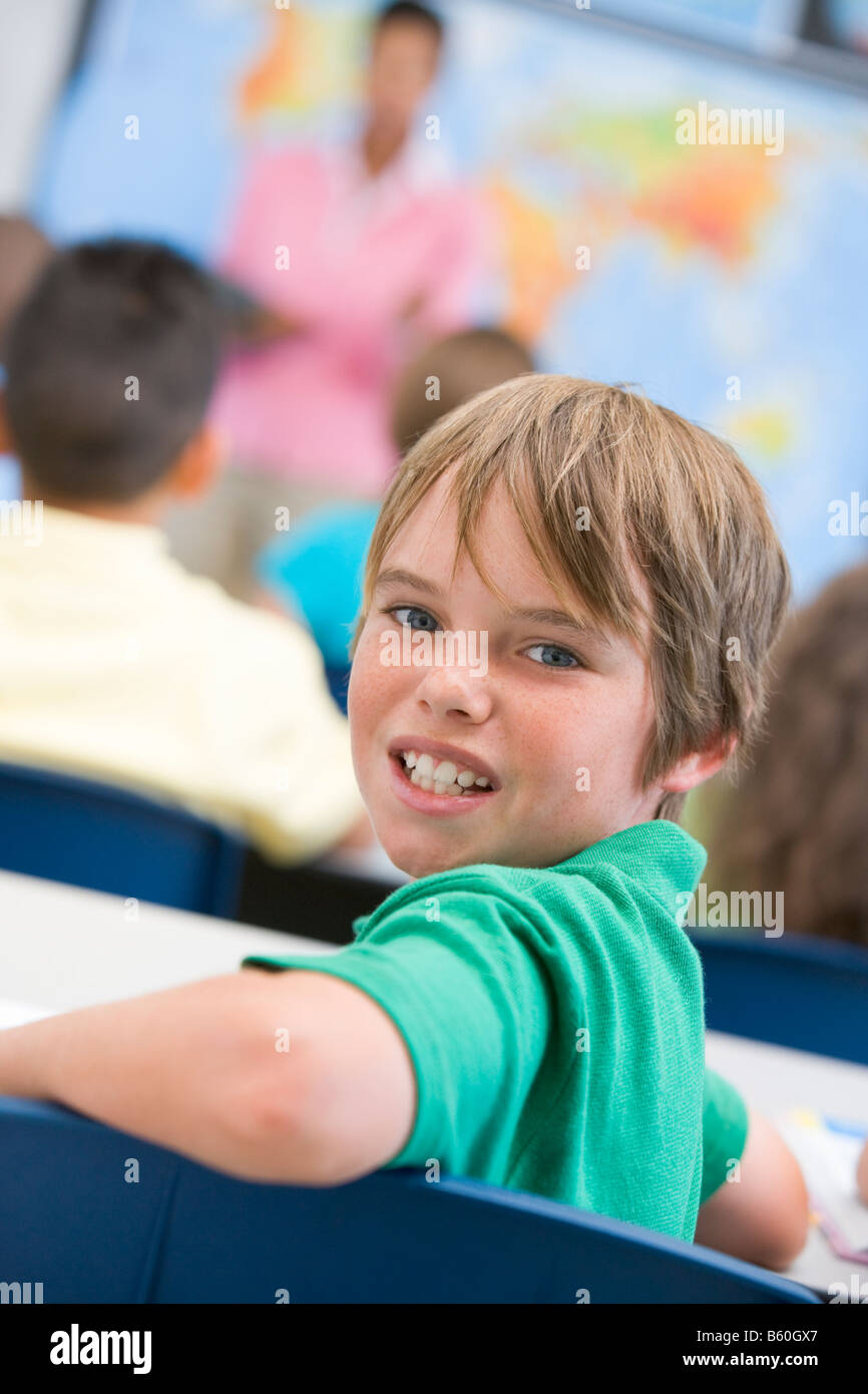 Student in class looking at camera with teacher in background (selective focus) Stock Photo