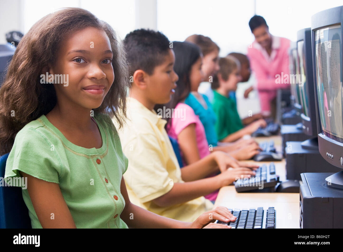 Six children at computer terminals with teacher in background (depth of ...