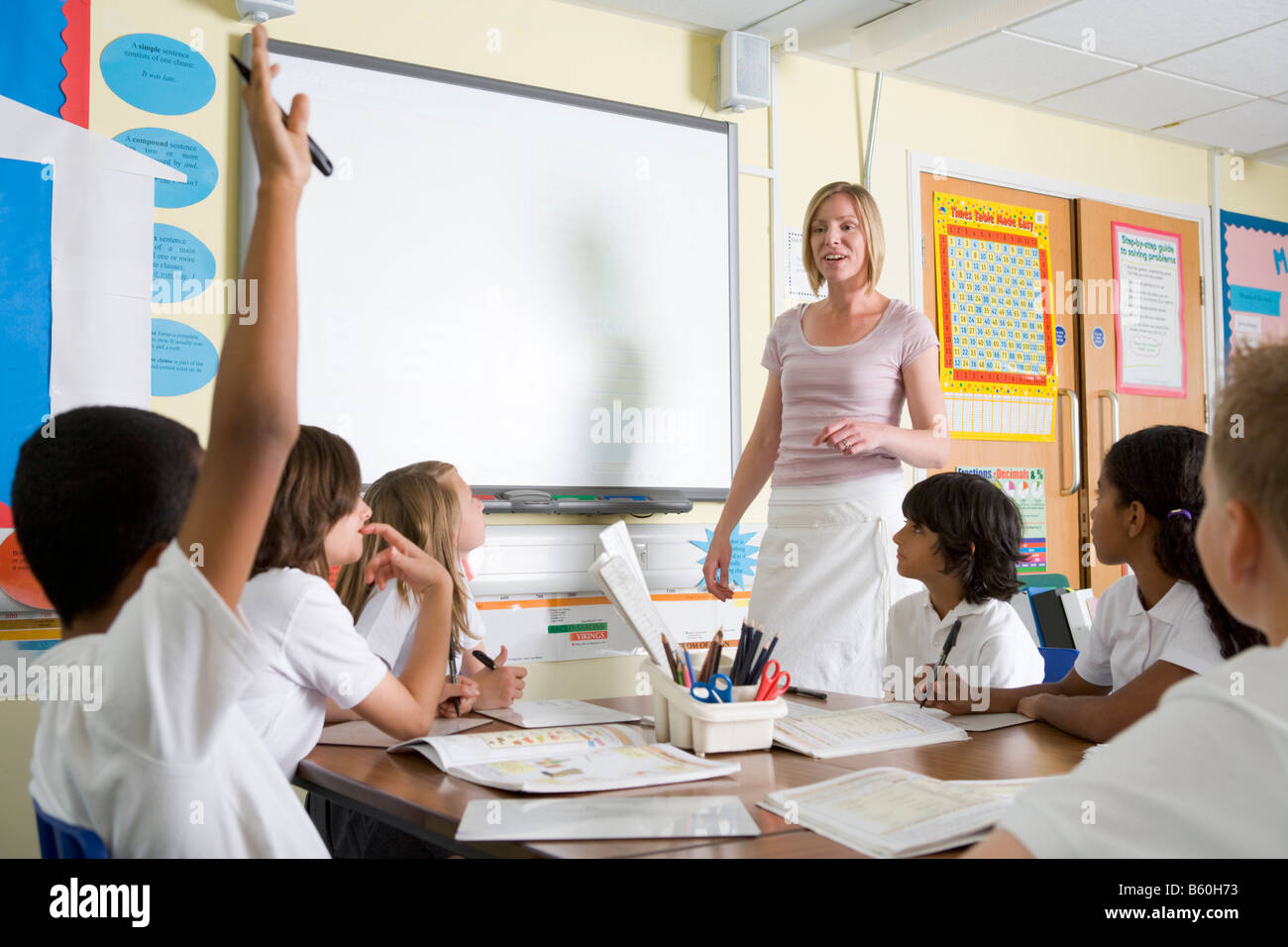 Student volunteering in class with teacher at board Stock Photo