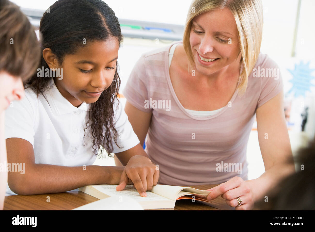 Student in class reading book with teacher Stock Photo