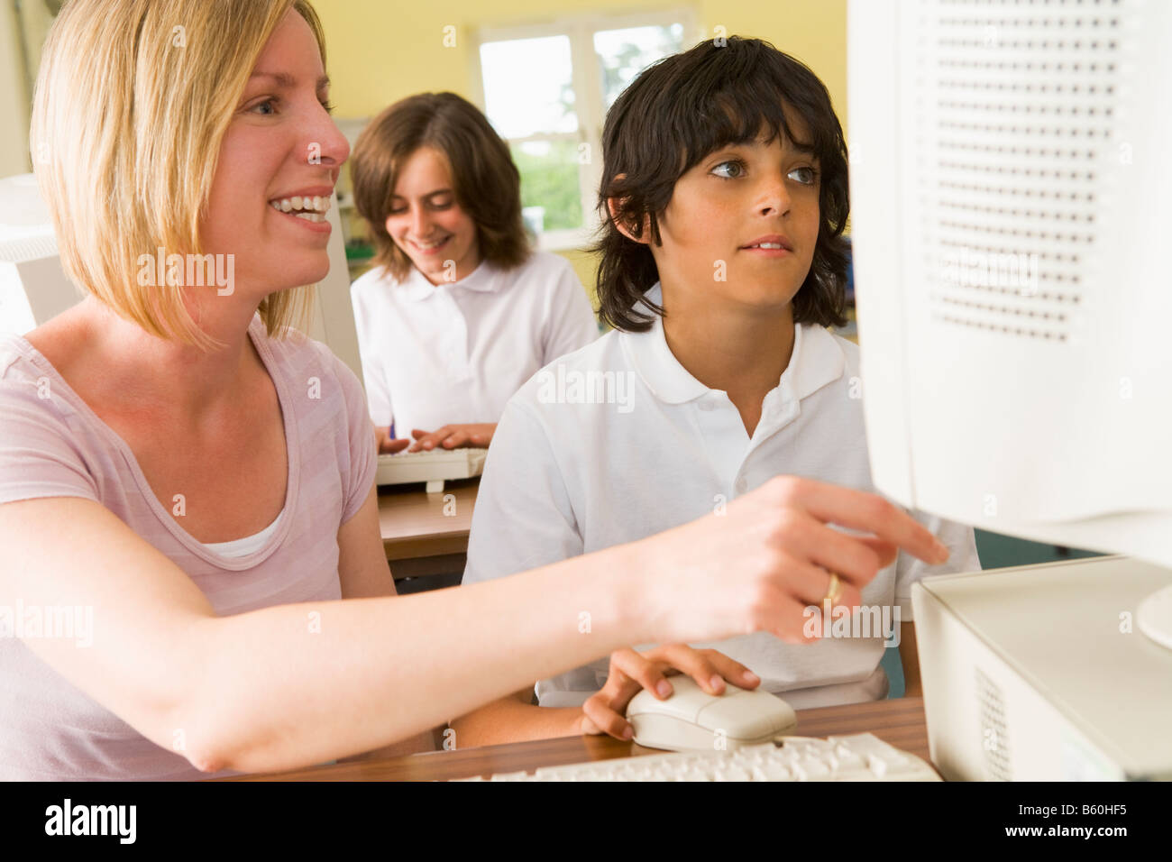 Student and teacher at computer terminal with student in background (selective focus) Stock Photo