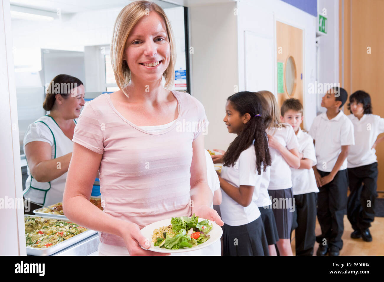 Students in cafeteria line with teacher holding her healthy meal and ...