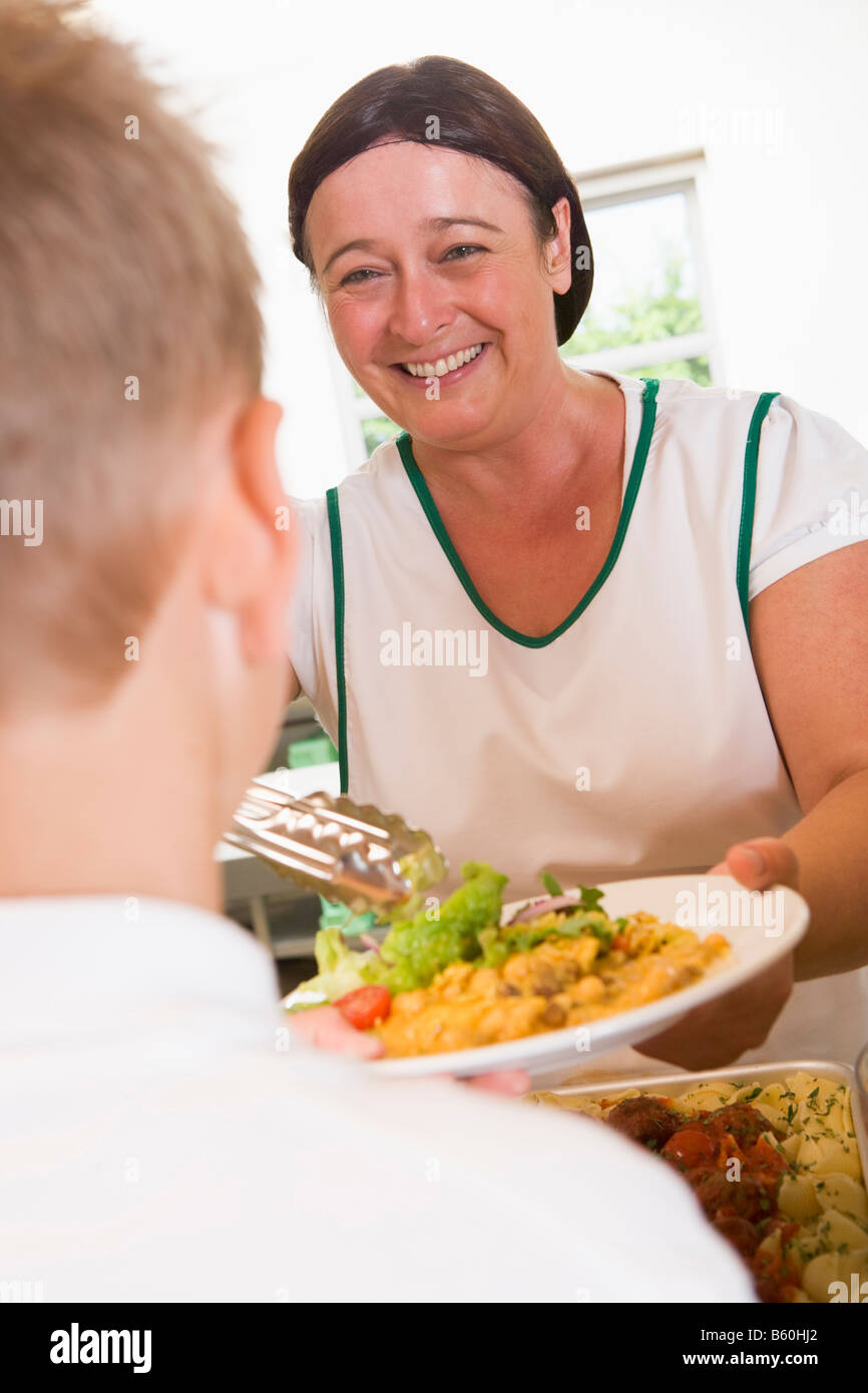 Lunch lady serving salad to student Stock Photo