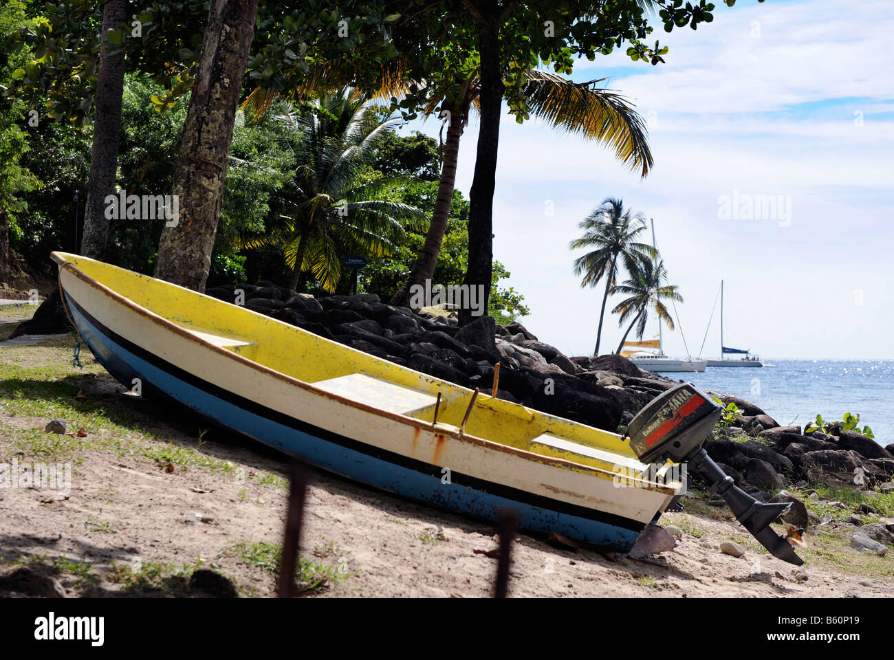 A SMALL FISHING BOAT IN THE COLOURS OF THE ST LUCIAN FLAG BY FORBIDDEN BEACH AT THE JALOUSIE PLANTATION RESORT ST LUCIA Stock Photo