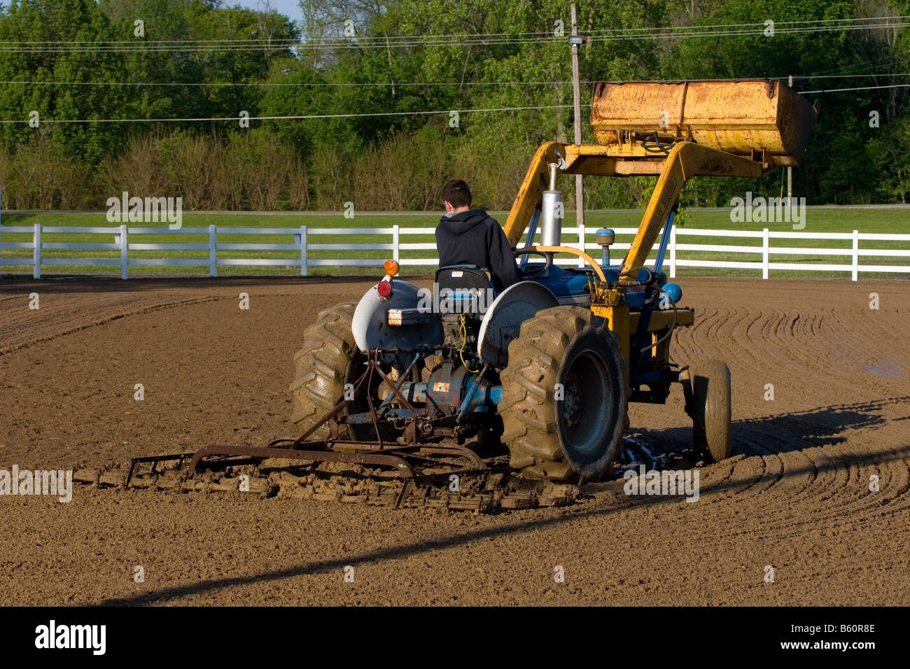 Tractor with bucket being used to drag a wet horseshow arena to level