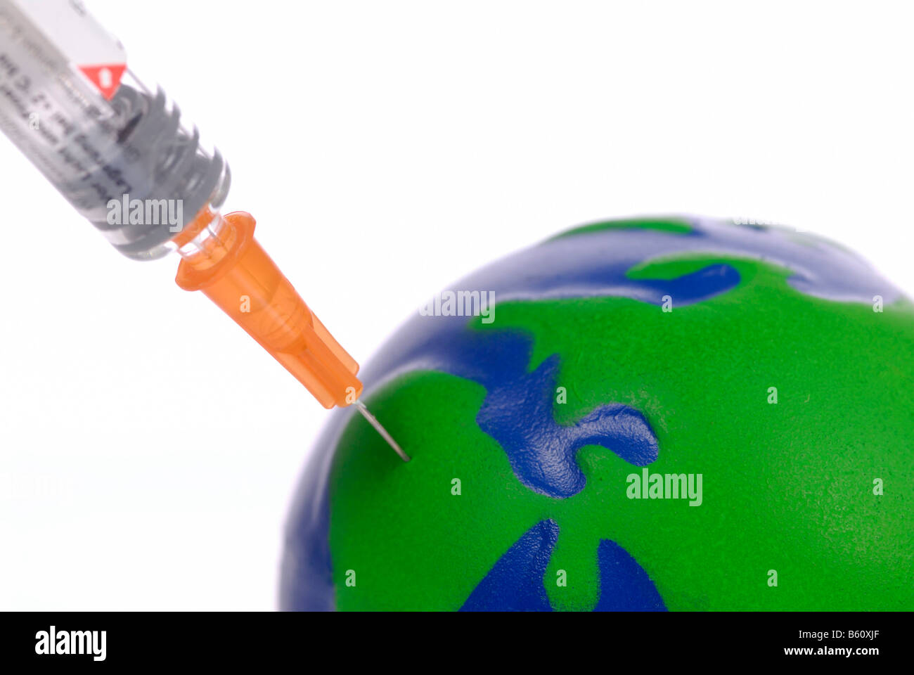 Inoculation syringe injected into a miniature globe, symbolic image for travel inoculation, climate change or environmental Stock Photo