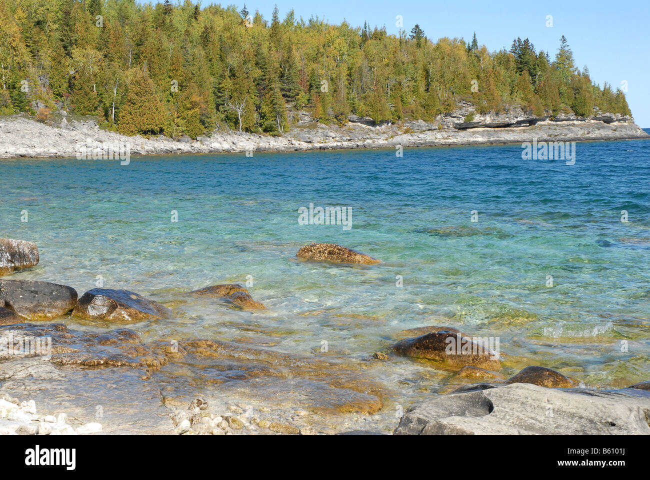 The bright blue waters of Bay against rocks and coniferous