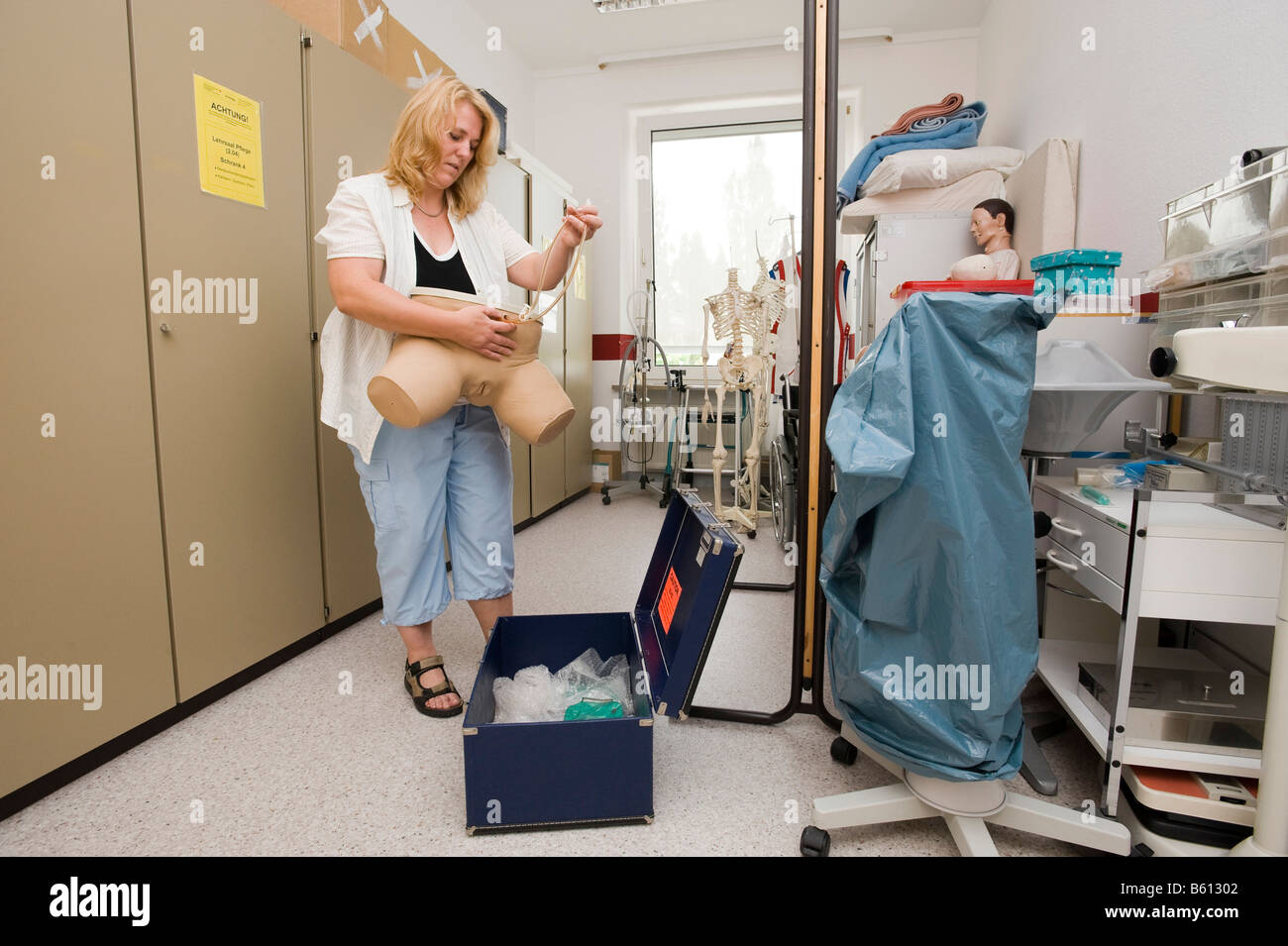 Geriatric care trainer prepares a dummy for catheter training in the teaching aid storeroom Stock Photo