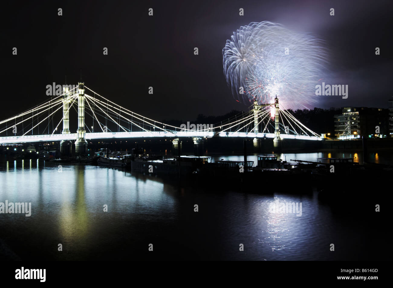 The Albert Bridge in Chelsea London lit up at night with the Battersea Park fireworks show taking place in the background Stock Photo