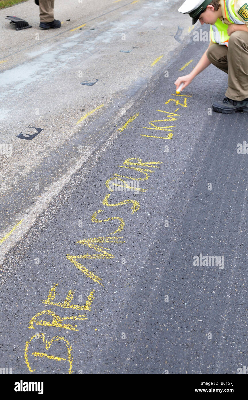 Young policewoman marking the road with crayon for accident expert