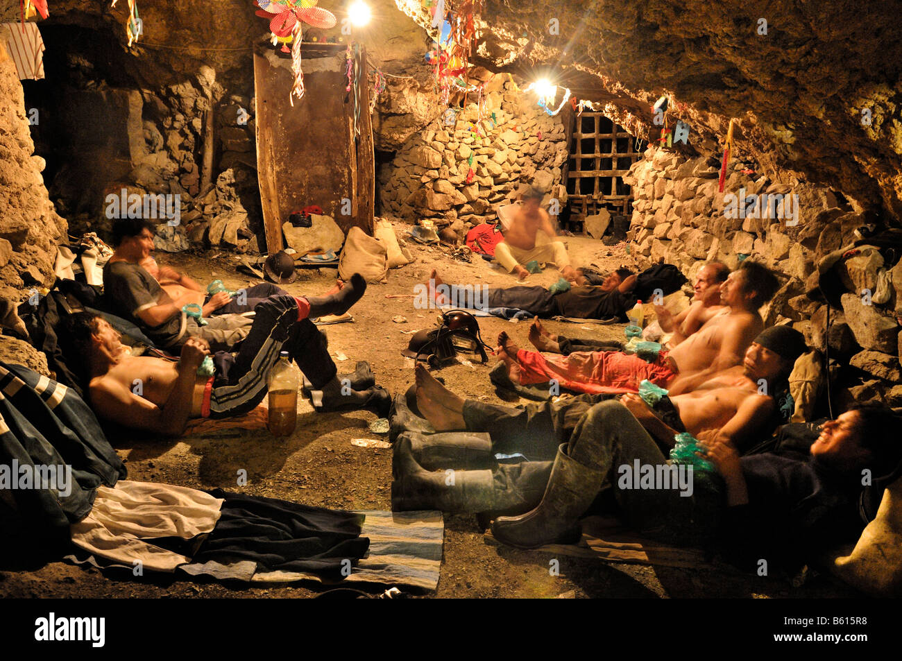 Miners resting, drinking alcohol and eating coca leaves before working in the tunnels, Llallagua mining centre, Potosi, Bolivia Stock Photo