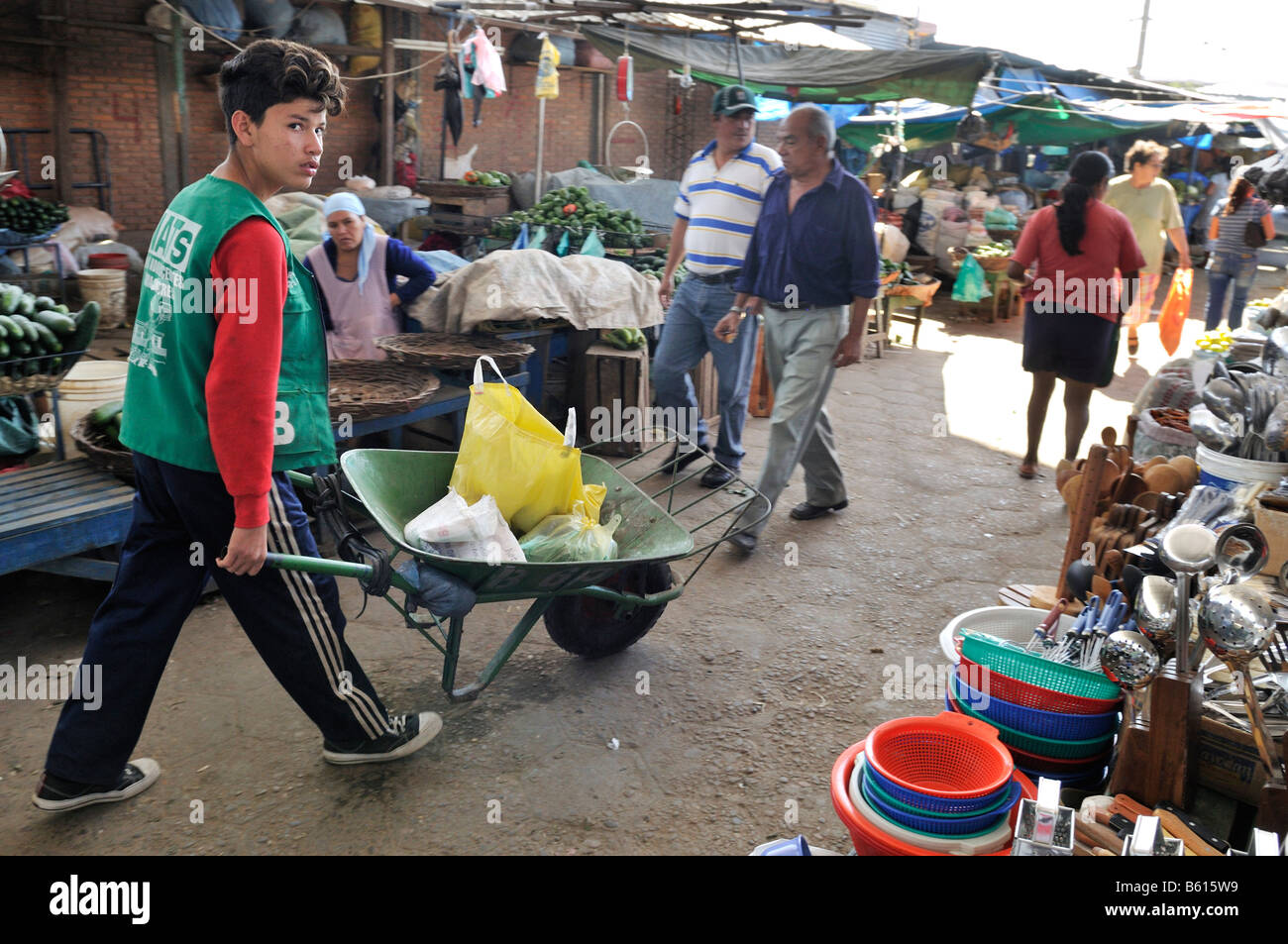Child labour, boy transporting customers' purchases using a wheel barrow at the local market, Santa Cruz, Bolivia, South America Stock Photo