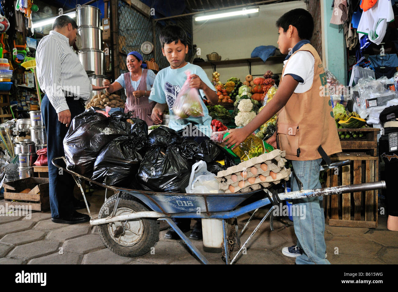 Child labour, boys transporting customers' purchases using a wheel barrow at the local market, Santa Cruz, Bolivia Stock Photo