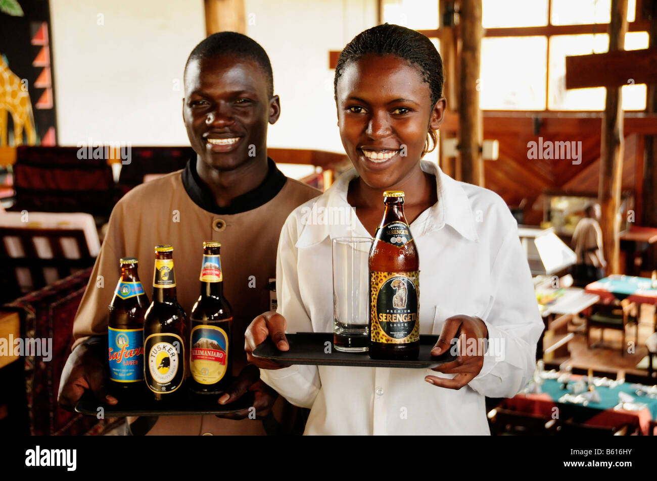 Waiter and waitress carrying the most popular beer brands in Tanzania, Serengeti, Kilimanjaro, Safari and Tusker Stock Photo