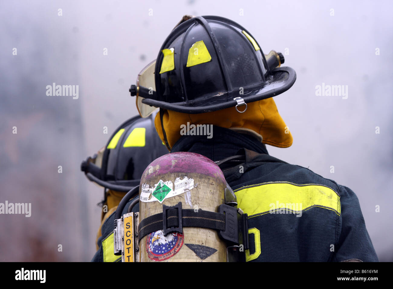 Two fire fighters surrounded by smoke while putting out a fire Stock Photo