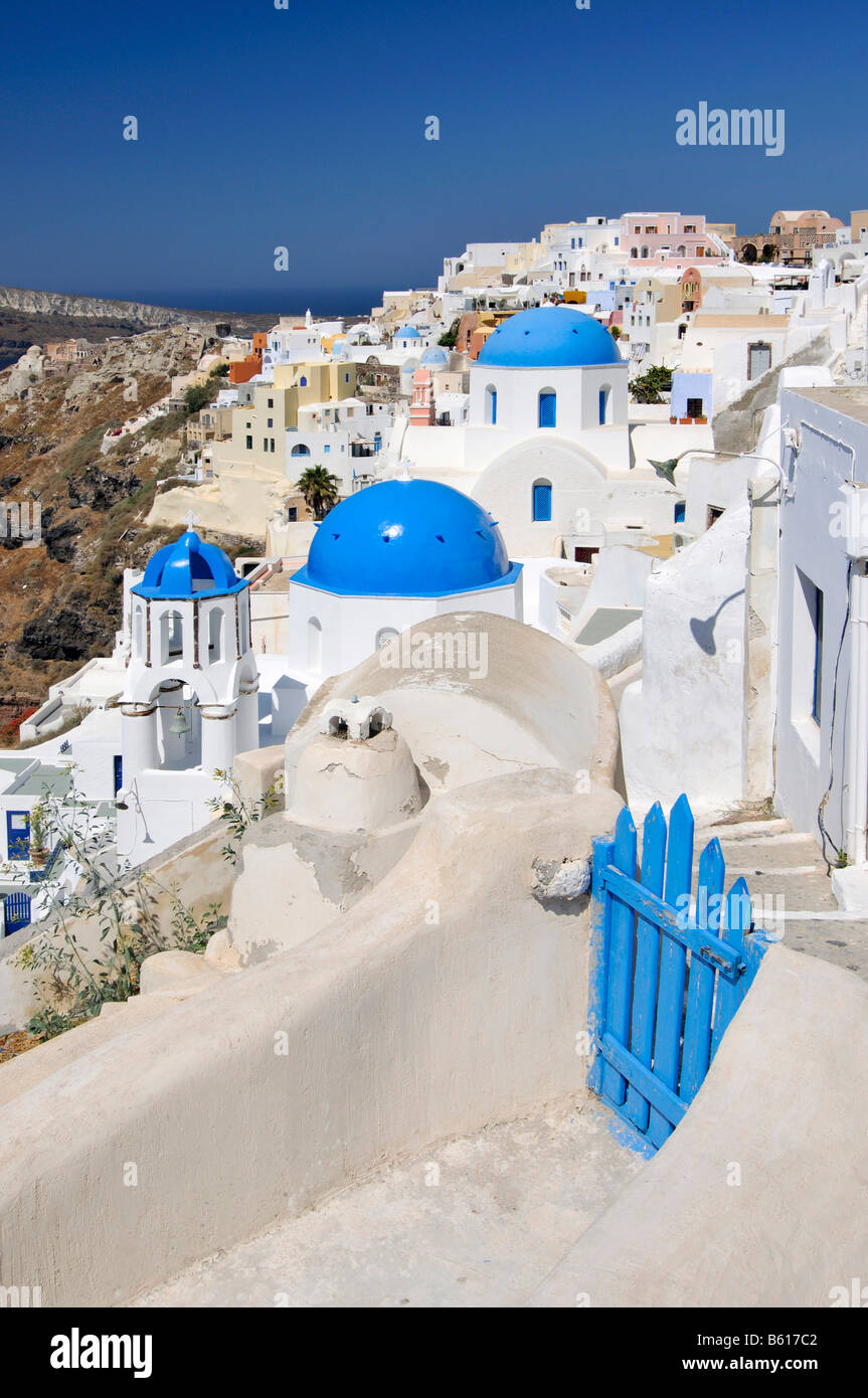 Blue and white domed church and a blue wooden gate in front of interlocked houses in the town of Oia, Ia, Santorini, Cyclades Stock Photo