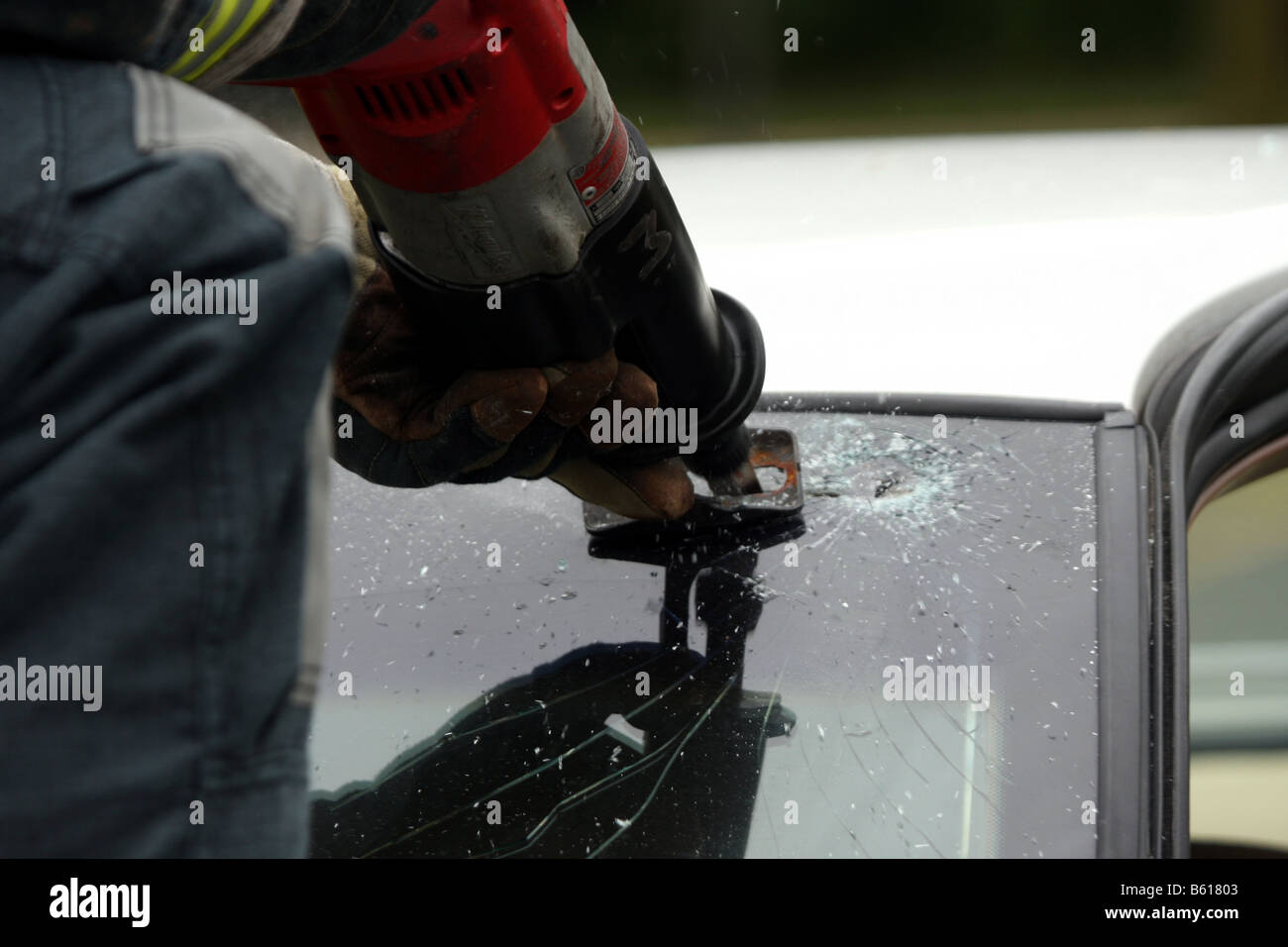 A firefighter on the hood of a car cutting the glass windshield during
