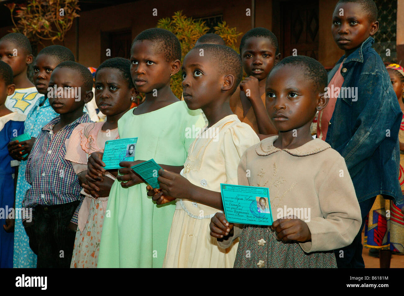 Children displaying their school identification documents for permission to receive school materials, Women's Education Centre Stock Photo