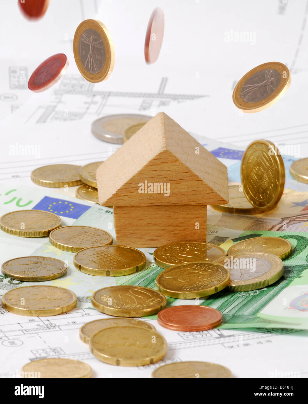 Little wooden houses on Euro notes and a building plan, coin falling from the sky, raining money, symbolic picture for house Stock Photo