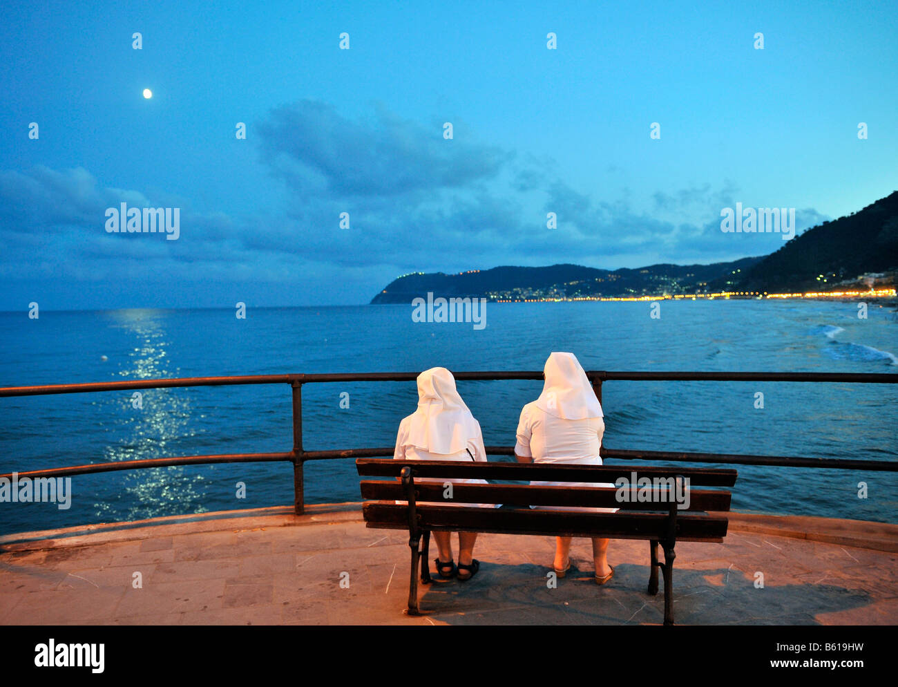 Two nuns sitting on a bench enjoying the view of the sea on the coast of Alassio, Riviera dei Fiori, Liguria, Italy, Europe Stock Photo