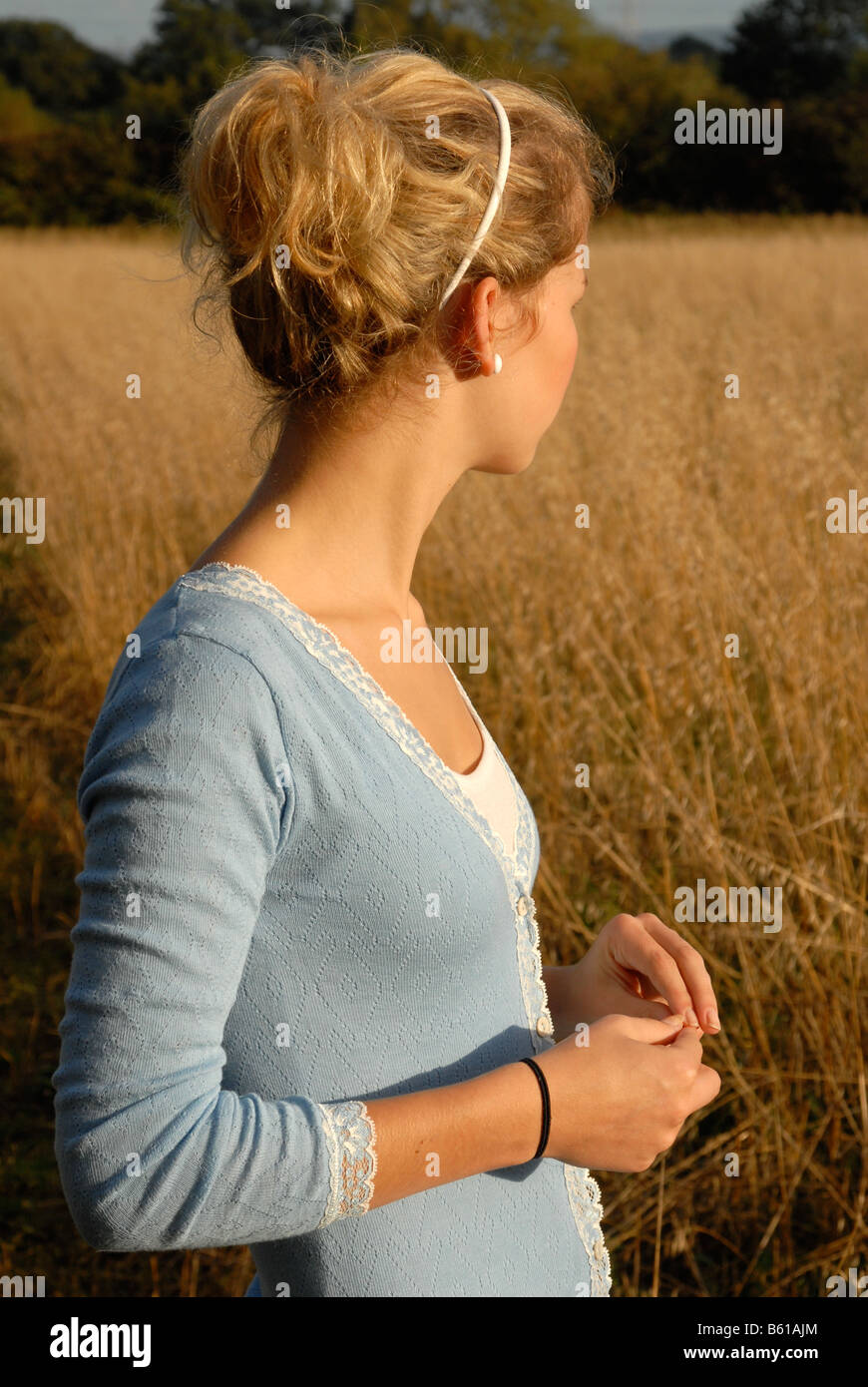 Teenage girl standing in a field looking away Stock Photo - Alamy