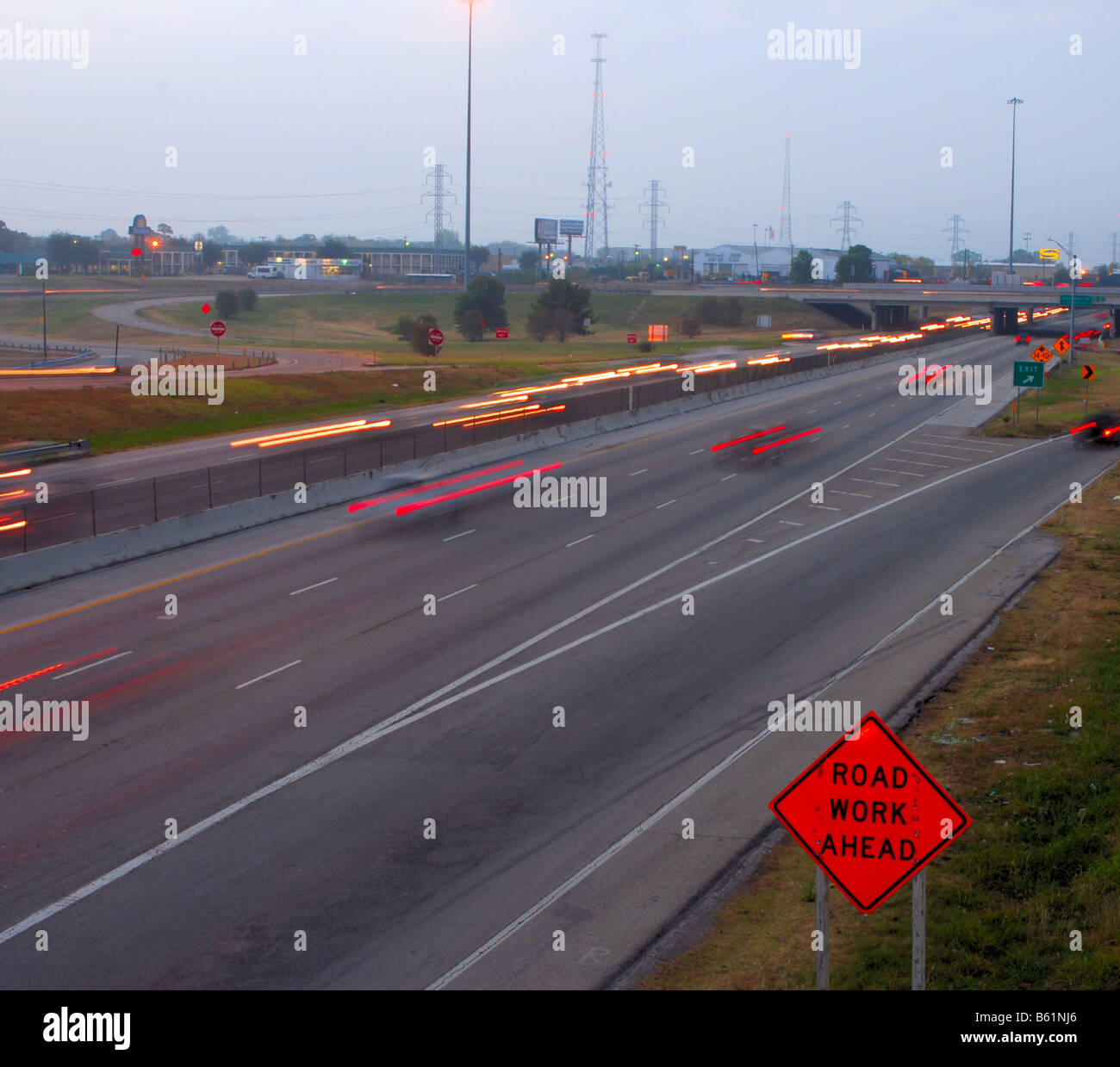 blurred image of fast traffic with road construction sign on left side