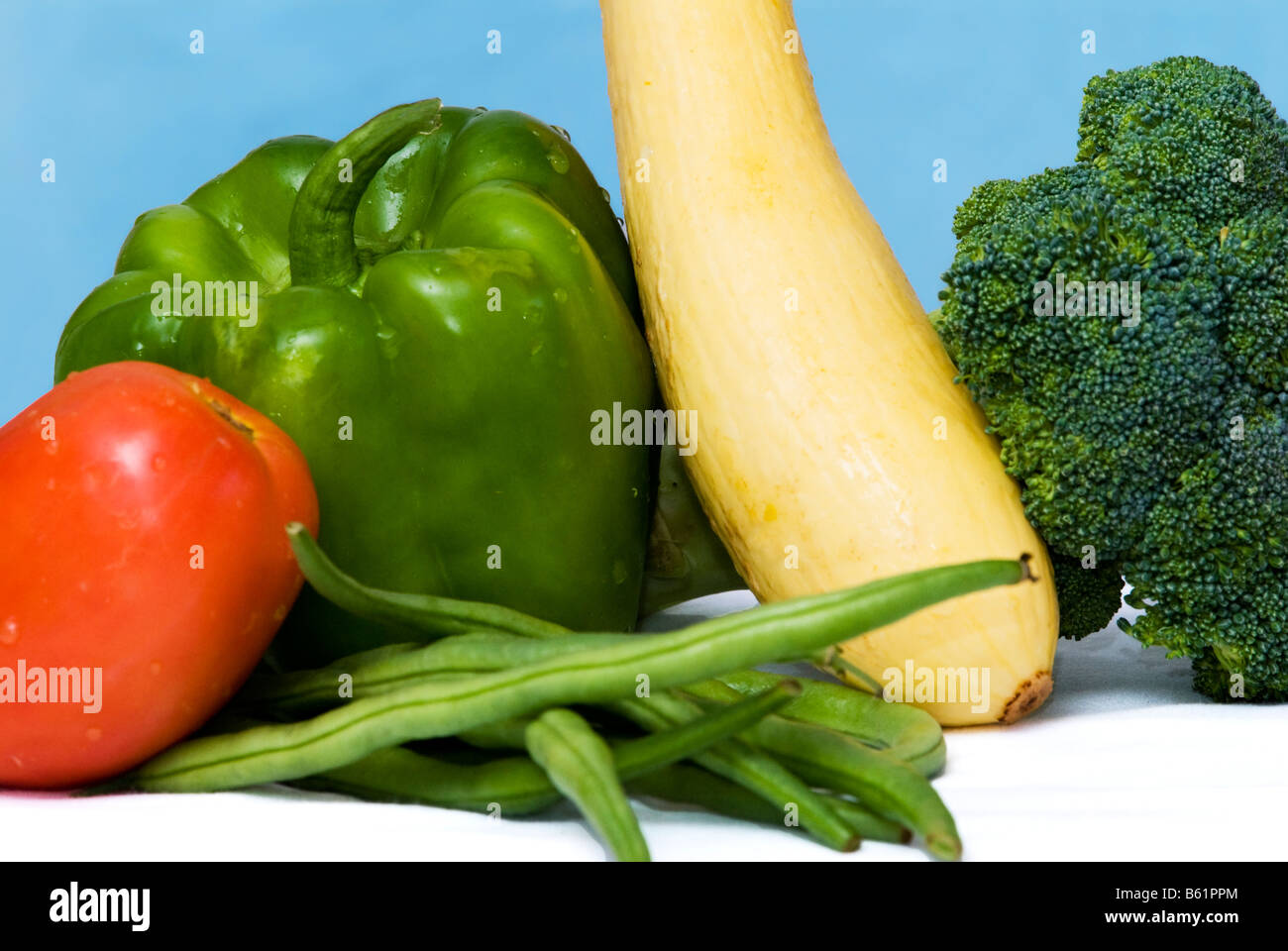 A closeup view of fresh, whole vegetables including Roma tomato, green