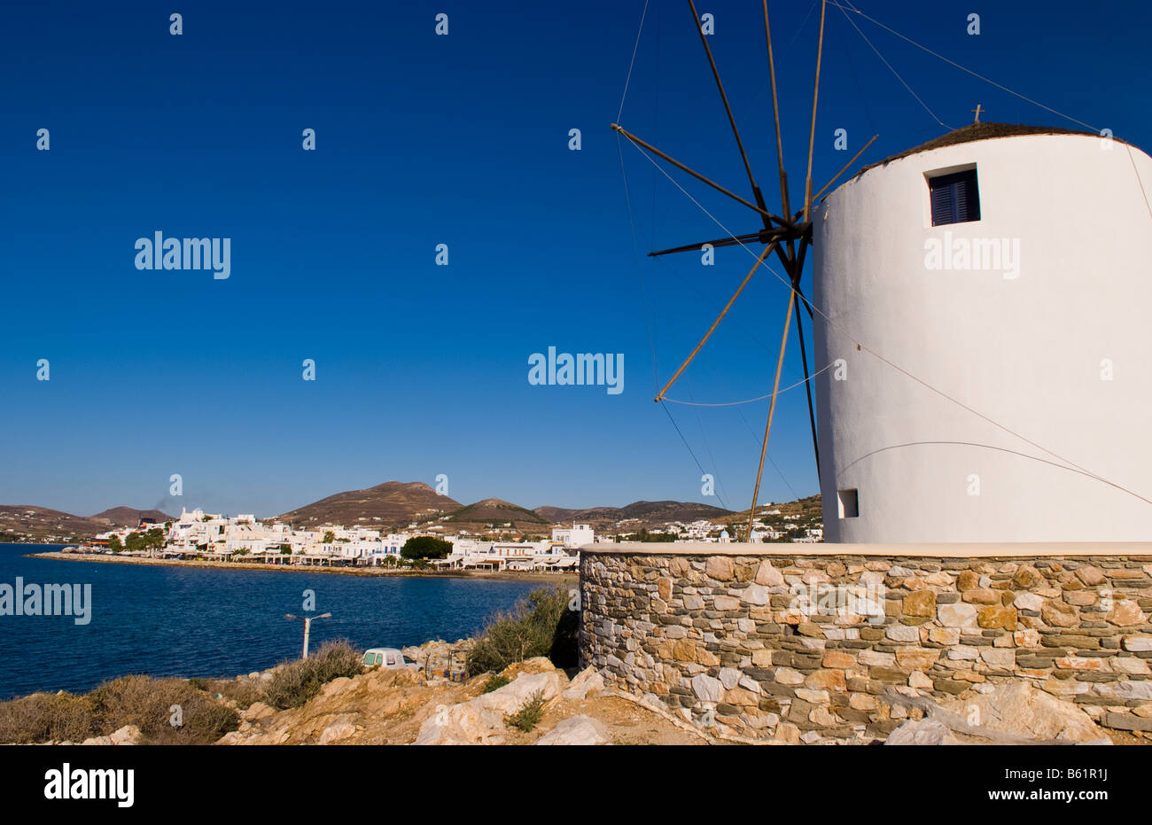 Famous windmill in harbor with center of city of Parikia capital city ...