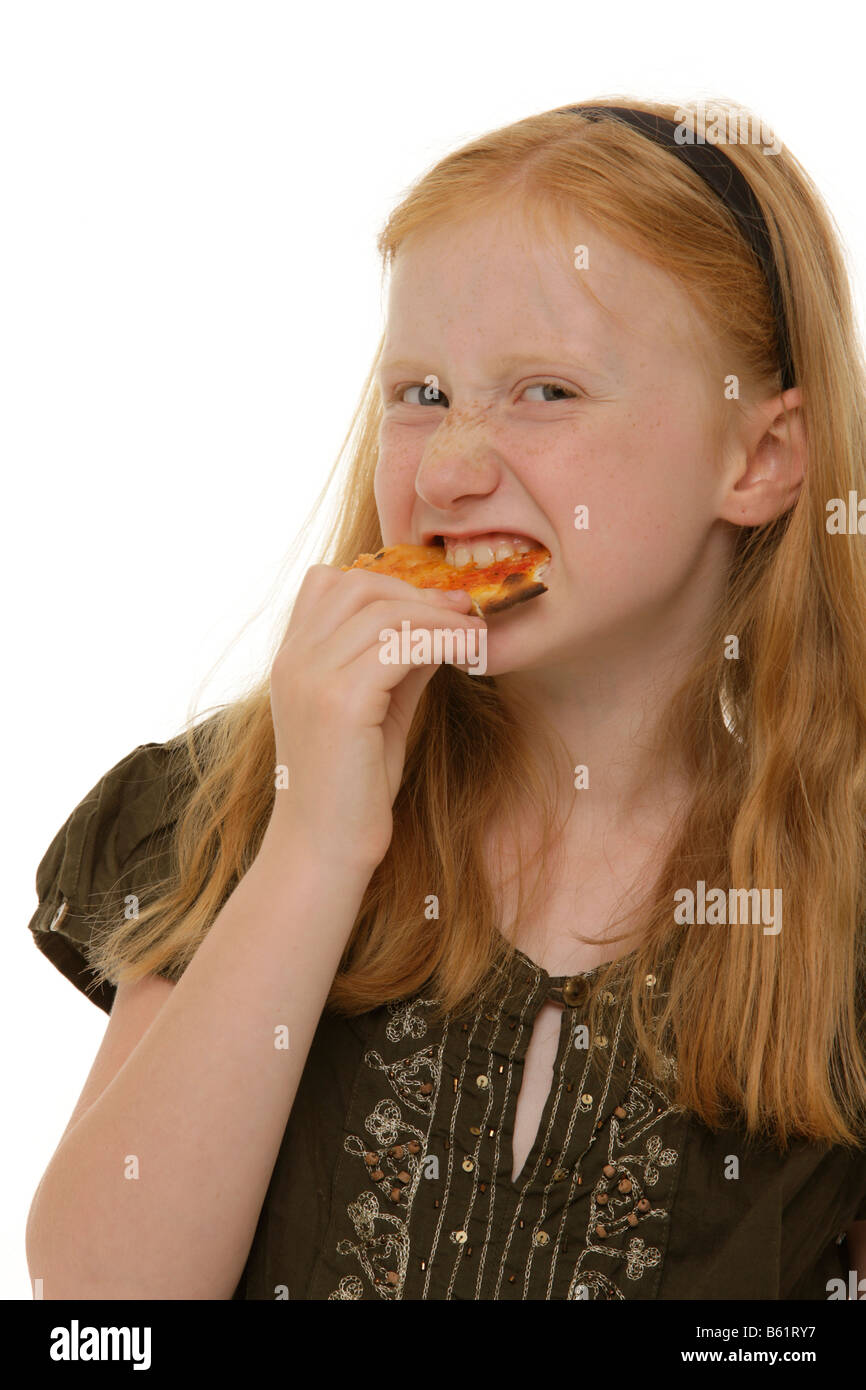 Girl, 8, biting heartfully into a piece of pizza Stock Photo