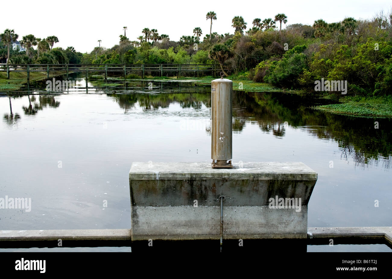 Metal cylinder on a concrete base by a tranquil lake in Florida Stock Photo