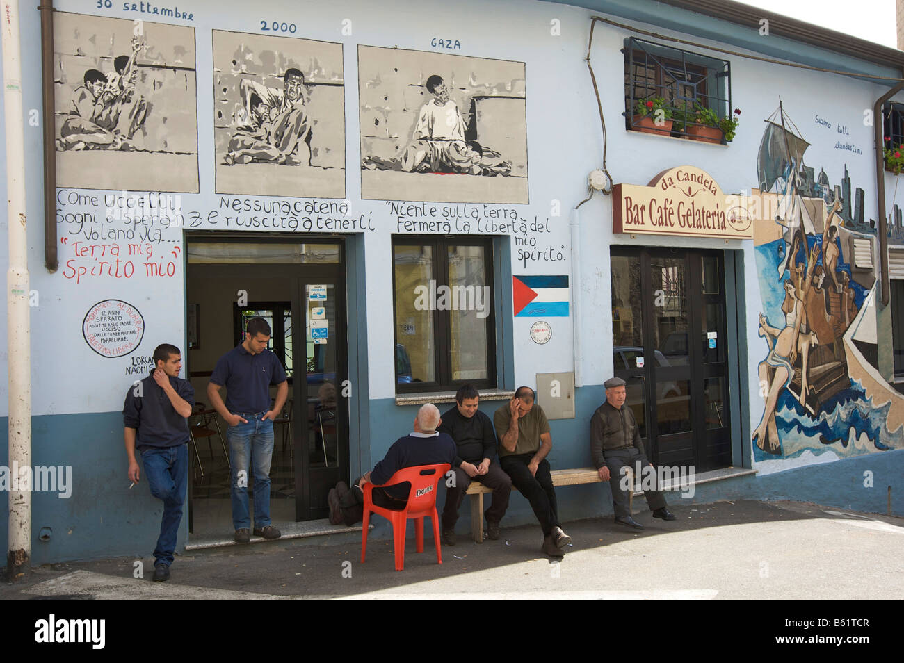 Men in front of a café painted with political murals, Orgosolo, Sardinia, Italy, Europe Stock Photo