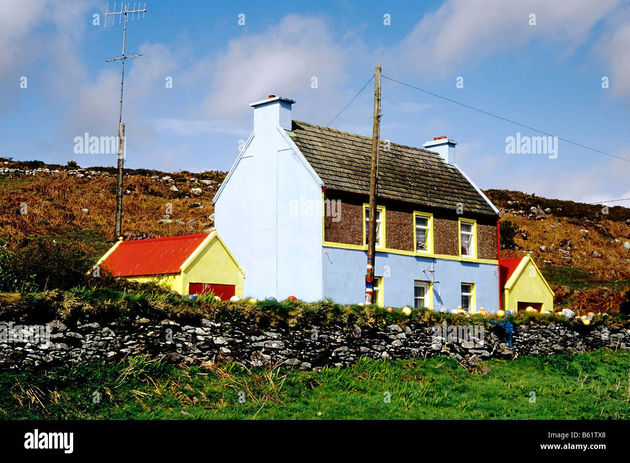 Brightly painted small house behind a stone wall, near Clifden