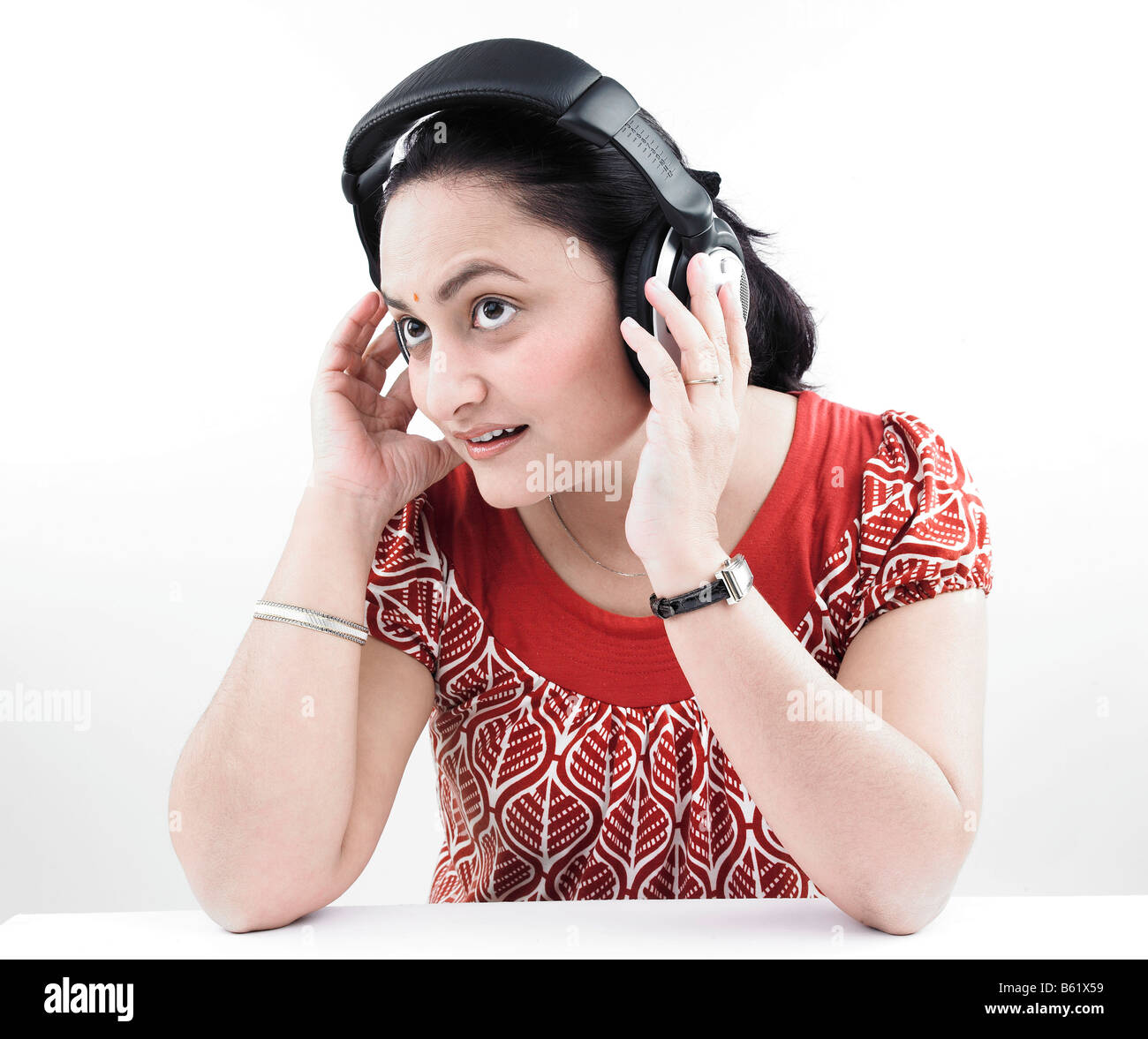asian woman of indian origin listening to music with her headphones on Stock Photo