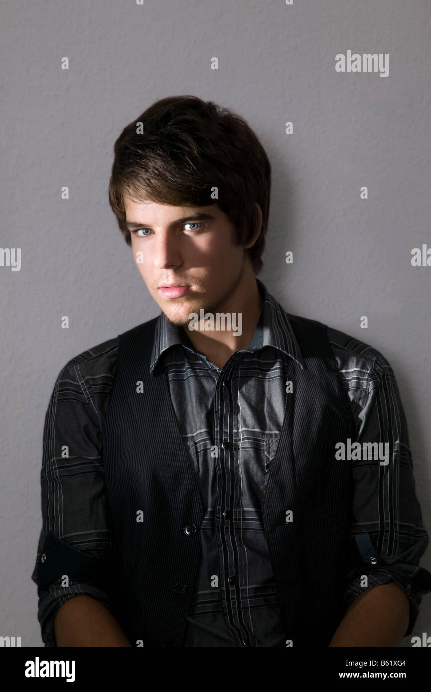 Young man sitting confidently in front of a wall Stock Photo - Alamy