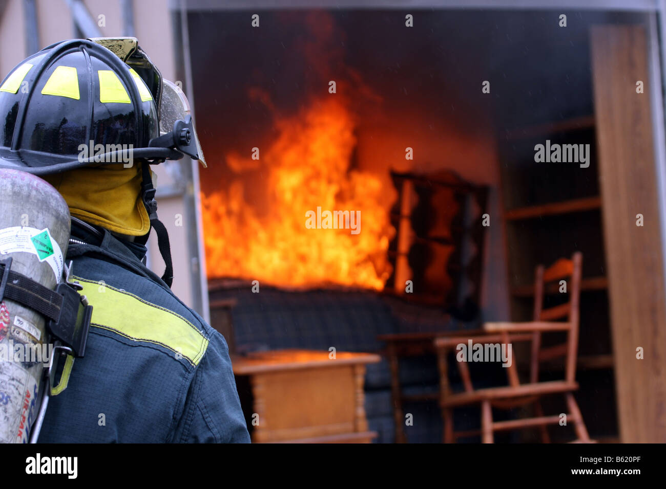A fire fighter ready to fight a fire in a container full of furniture Stock Photo