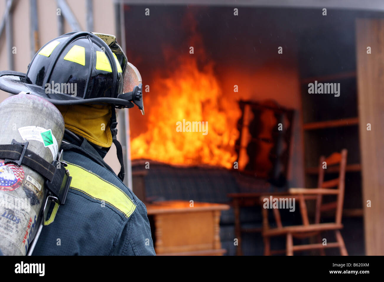 A fire fighter ready to fight a fire in a container full of furniture Stock Photo