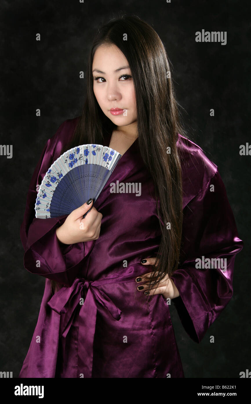 Portrait of a Young Chinese Girl Wearing a Purple Dressing Gown and Holding a Blue Fan Stock Photo
